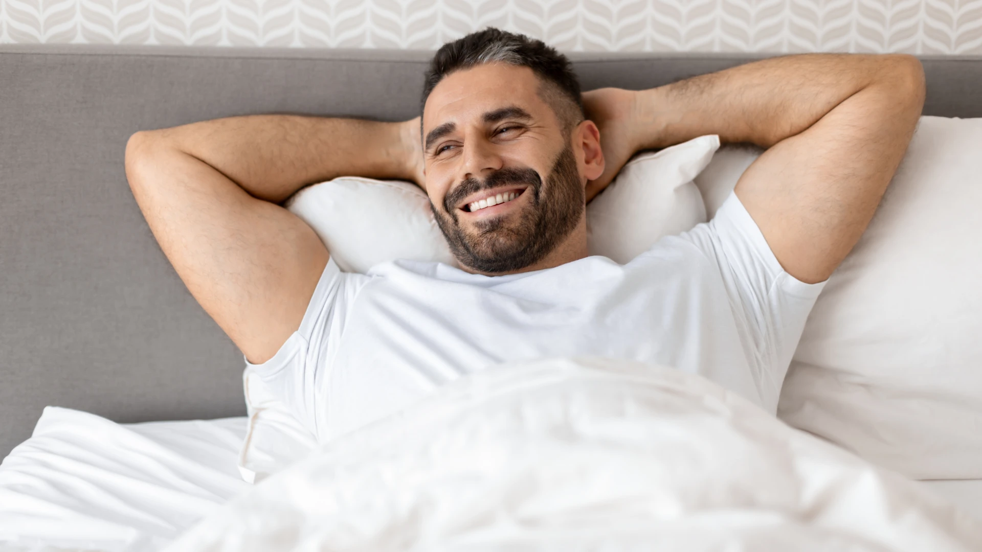 homme heureux assis dans son lit se sentant fier