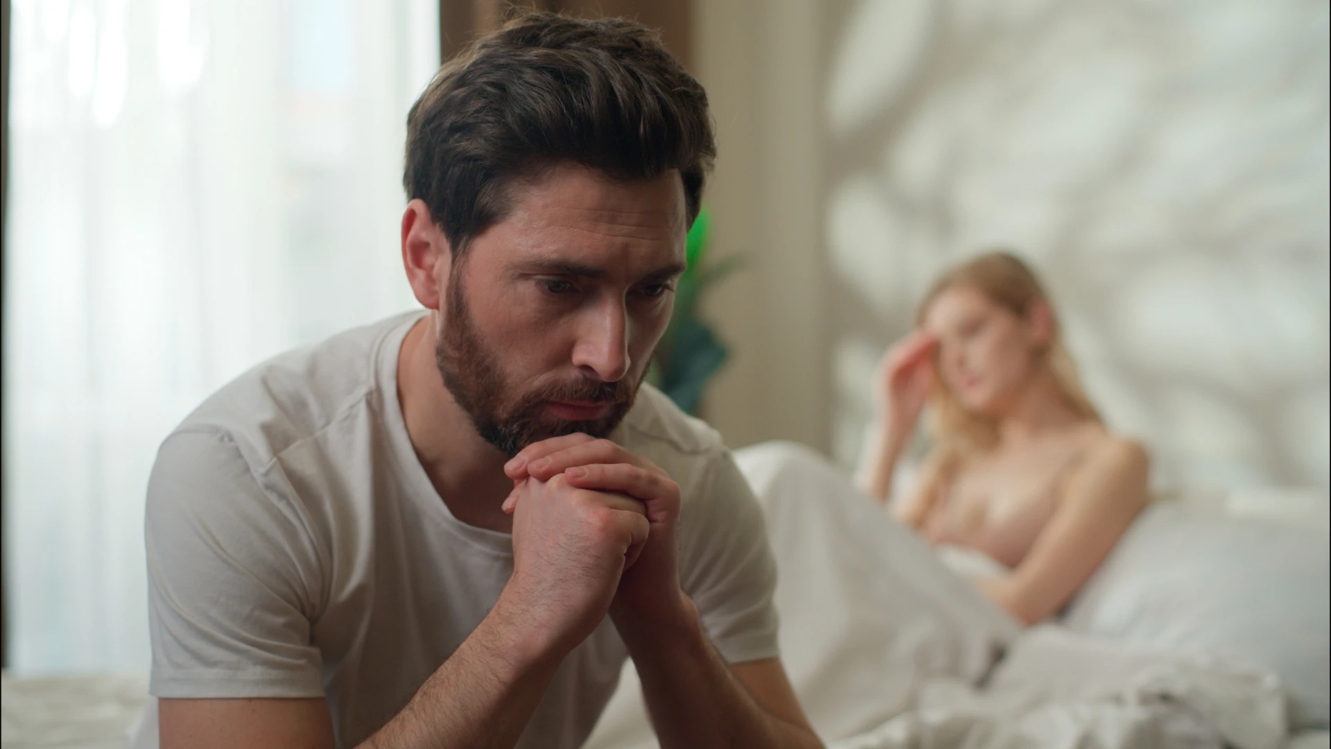 homme en détresse assis loin de sa femme au lit