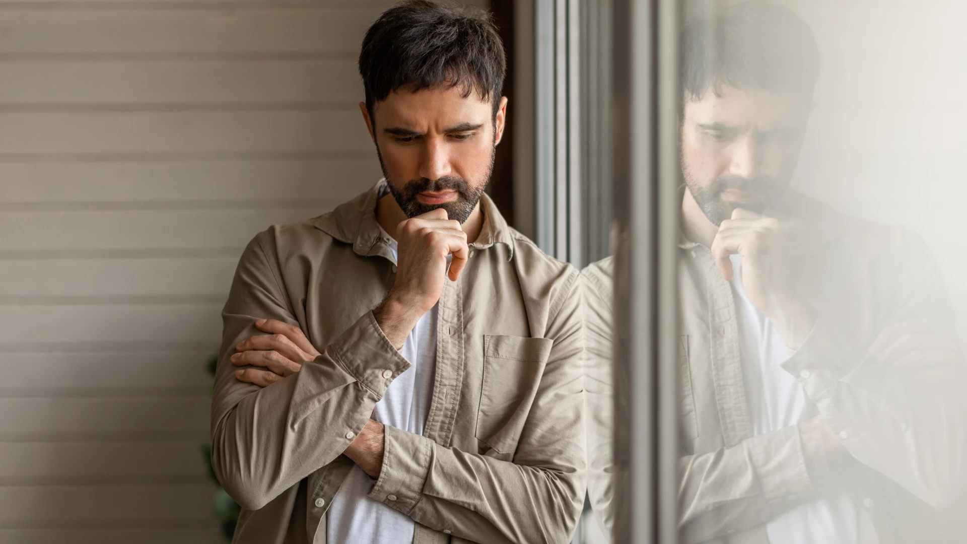 homme pensant en se tenant à côté de la fenêtre