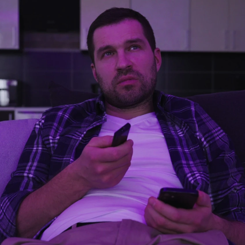 homme malheureux regardant la télévision sans réfléchir en utilisant des mécanismes d'adaptation malavisés