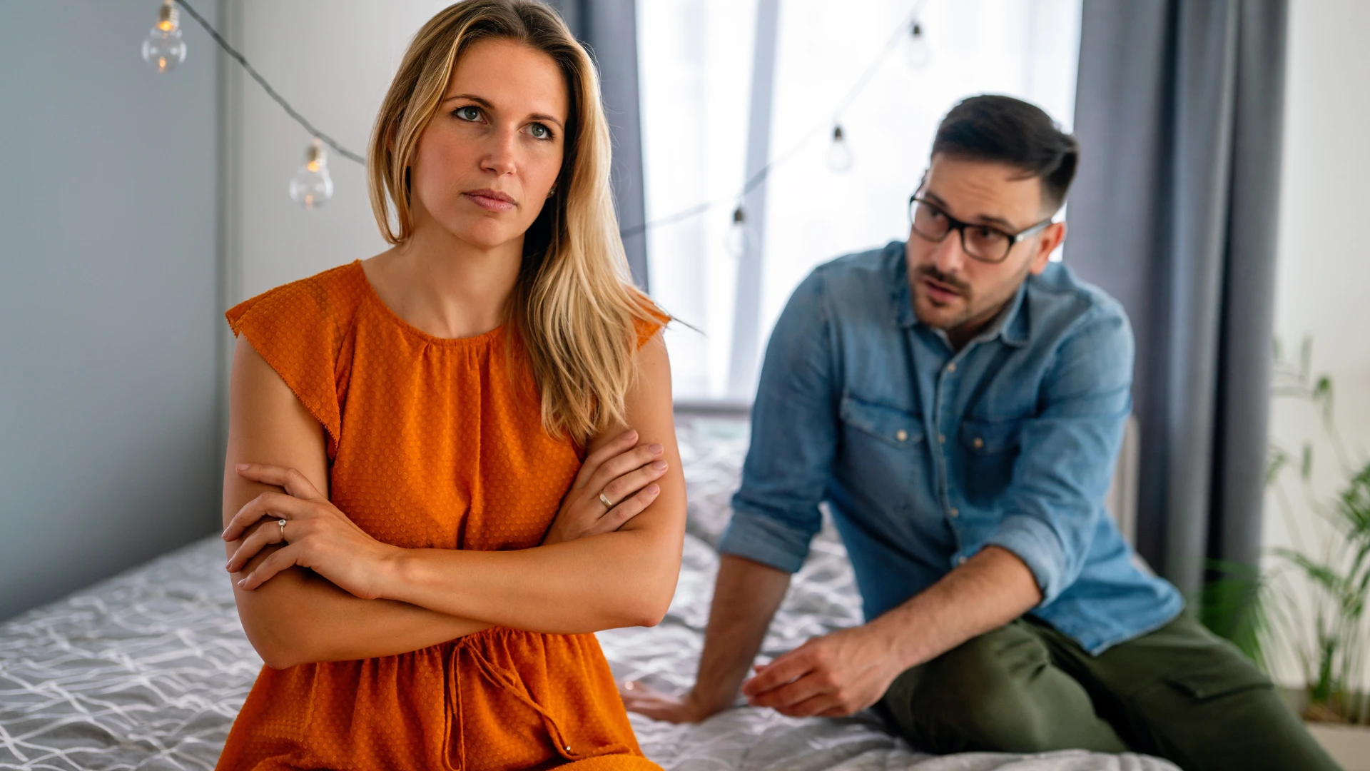couple assis sur le lit femme disant que je ne suis pas d'humeur