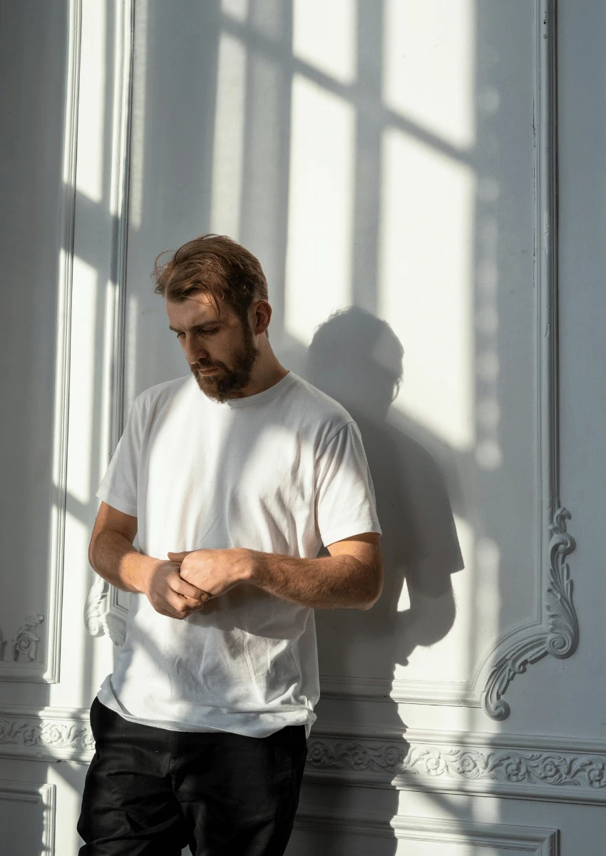 homme peu sûr de lui, debout contre un mur