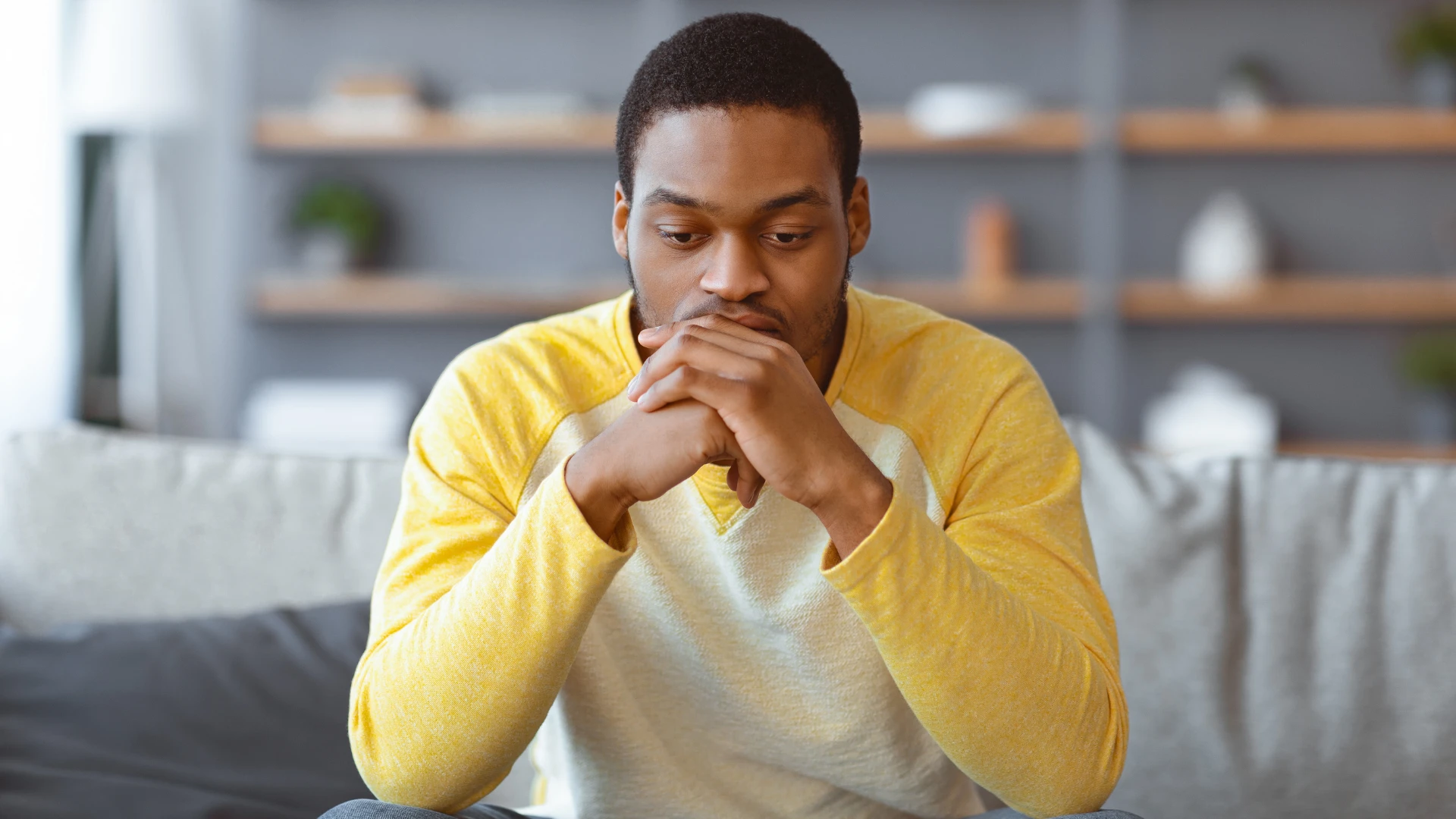 homme bouleversé assis sur un canapé ne montrant aucune empathie