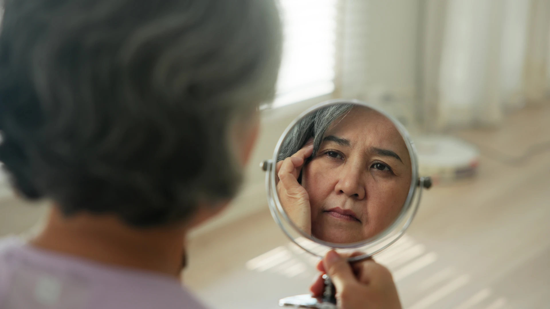 Une personne contemplative se regarde dans un miroir, montrant une conscience post-divorce