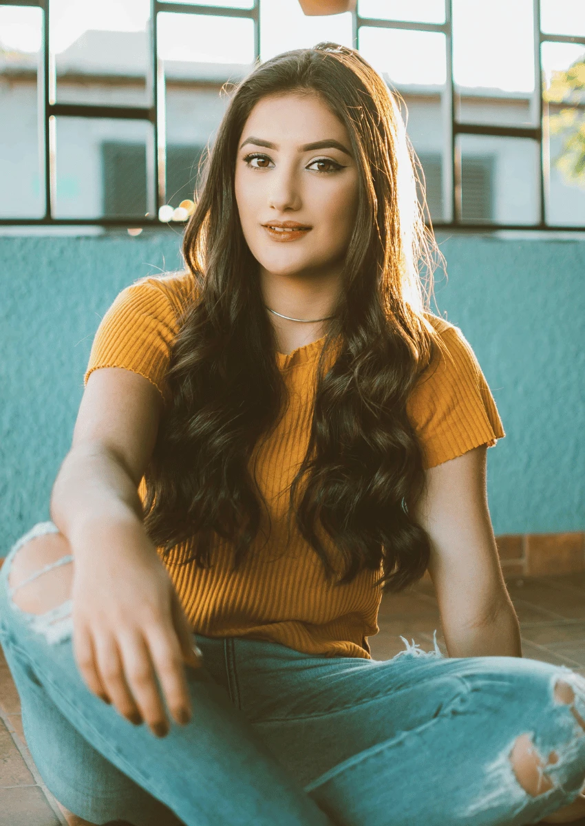 jeune femme portant un jean déchiré et assise par terre