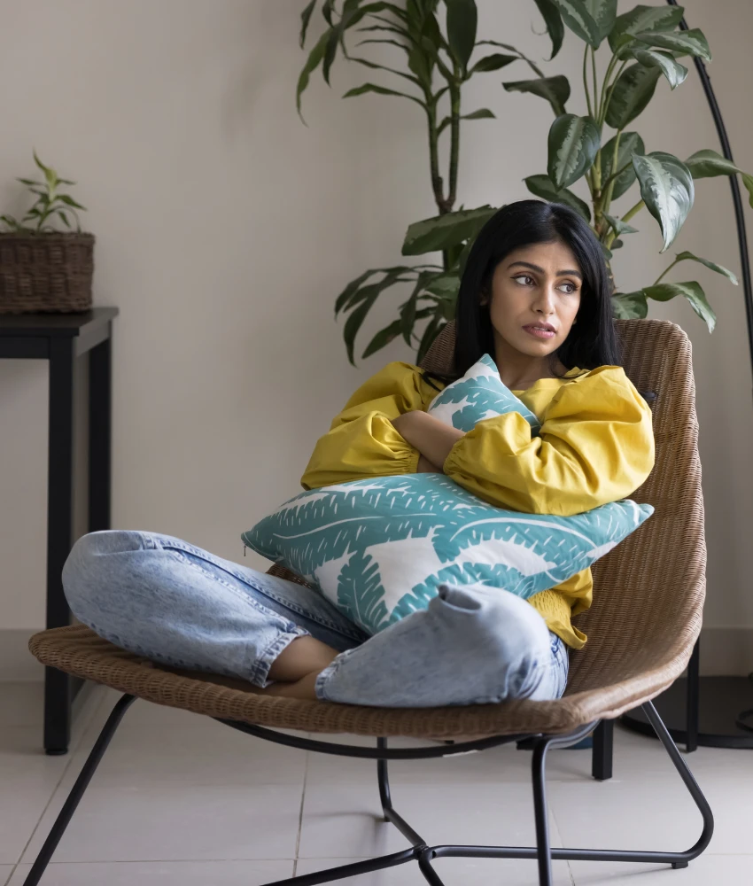 une personne anxieuse dans une chaise embrasse un oreiller montrant qu'elle a du mal à faire face